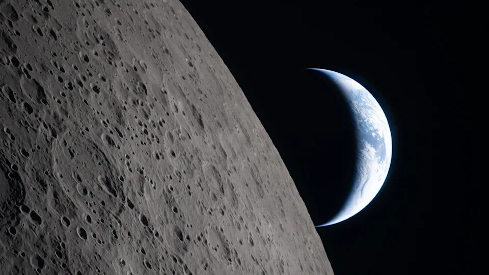 Earth seen from the moon. Half of the Earth is illuminated, and the gray surface of the Moon is visible in the foreground.
