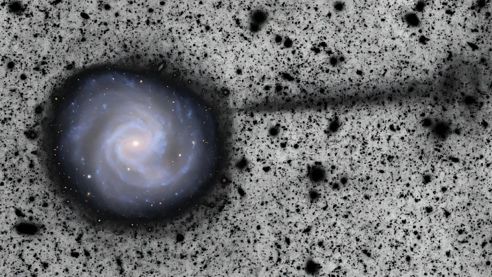 Image of a spiral galaxy on a speckled black and white background with streams of black material coming out of the galaxy