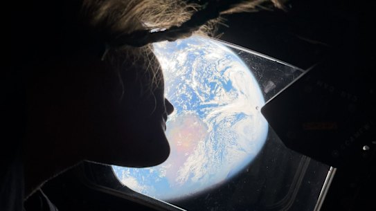 Christina Koch stares at Earth through one of the windows in the main cabin of the Orion spacecraft.