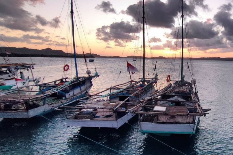 Wooden ship moored in the harbor at sunset.