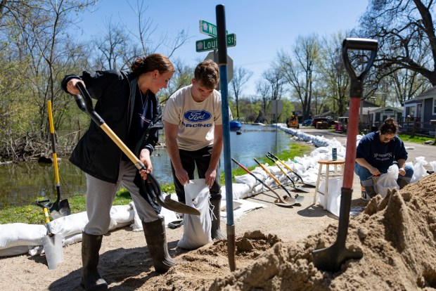 Josie Bell (left) and Ryan Heuser fill sandbags along Beach Street as the Fox River rises in Crystal Lake on April 20, 2026. (Brian Cassella/Chicago Tribune)
