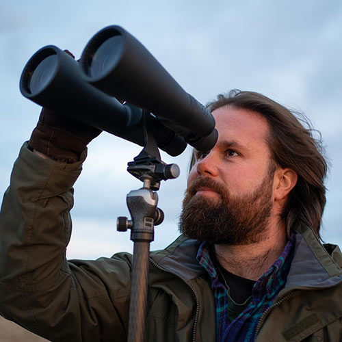 The author stares at the sky with large Celestron binoculars in hand.